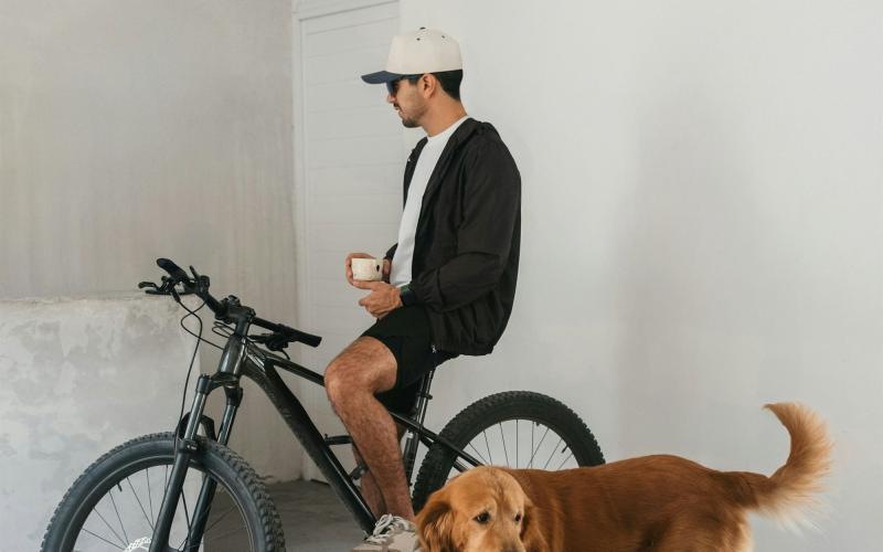 a man sitting on a bike next to a dog